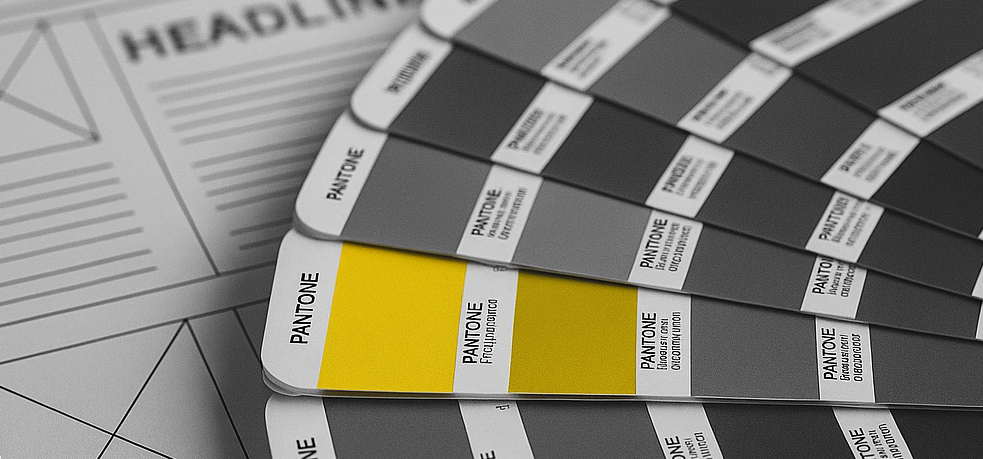 Ein Kompass mit gelber Nadel und einem Steuerrad im Hintergrund, in Schwarz-Weiß-Optik.