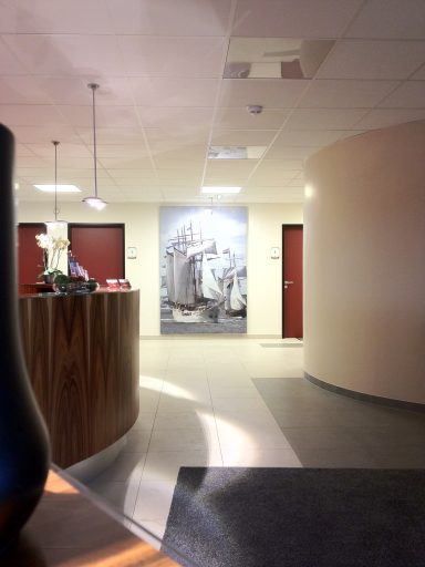 Moderne Empfangshalle mit runden Wänden, rot gefärbten Türen und einem Kunstwerk im Hintergrund.